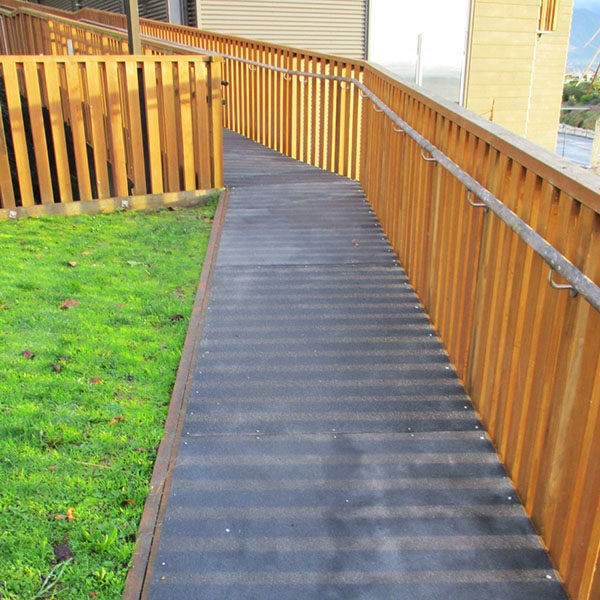 Black FRP anti-slip flat sheet walkway outside building.