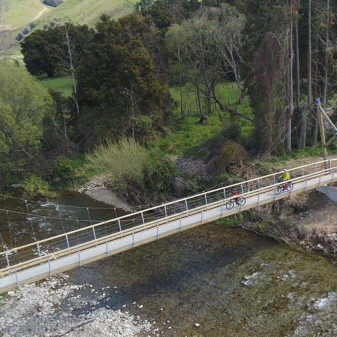 Cyclists on a swing bridge using FRP mini mesh grating.